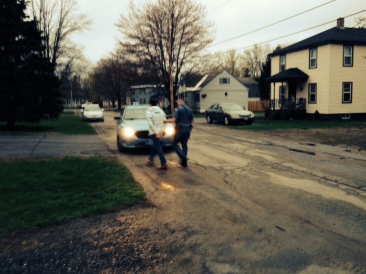 Police lead Andre Quirion to a waiting cruiser following his arrest Monday night in connection with a burglary last summer.