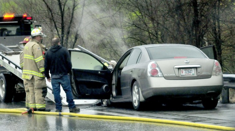 Smoke rises from the engine compartment of a car that caught fire while traveling in the northbound lane of I-95 near the Messalonskee bridge in Waterville on Monday. There were no reported injuries, and traffic was slowed to one lane until the vehicle was towed.