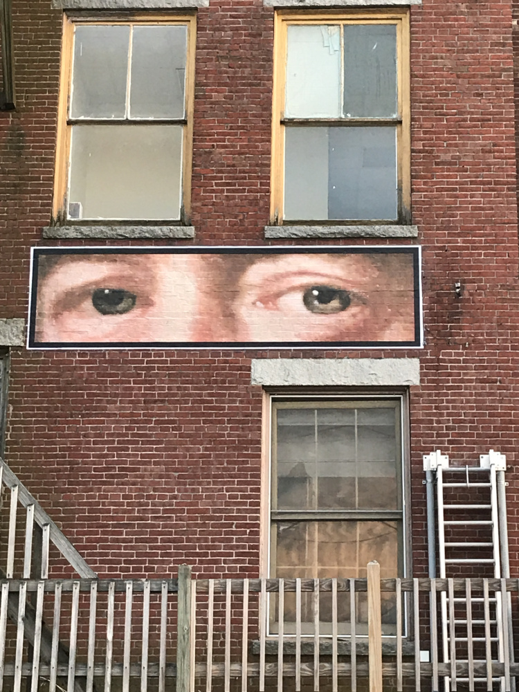 Kerstin Gilg revisits poet E.A. Robinson as an inspiration for his wheat paste project. In History Watching, Gilg has created three versions of the eyes of the Pulitizer Prize-winning poet, which look out over the Arcade parking lot and the Kennebec River in Gardiner. This exhibition is expected to remain in place until October.