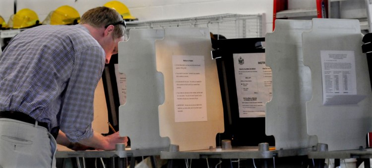 Luke Hartwell, a teacher in the Madison school system, casts his vote Tuesday for the SAD 59 school budget at the town fire department.
