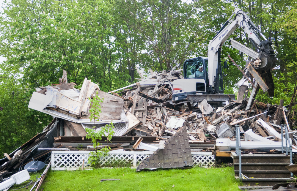 Driving a Bobcat excavator, Bob Anair demolishes 34 Main St. on Friday in downtown Richmond. The house across the street from the Old Goat Pub had been heavily damaged by a fire last Christmas.