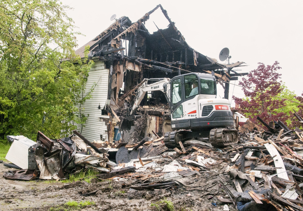 Staff photo by Joe Phelan
Driving a Bobcat excavator, Bob Anair demolishes 34 Main St. on Friday in downtown Richmond. The house across the street from the Old Goat Pub had been heavily damaged by a fire last Christmas.