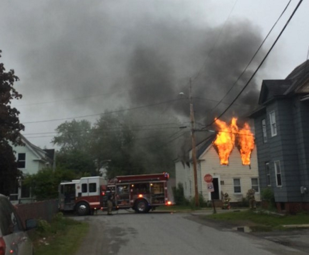 Flames shoot out of the second-story front windows of this Spruce Street house Thursday morning, displacing six adults and two children.