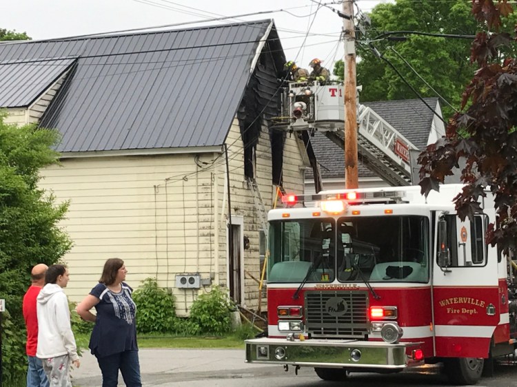 Officials work at the scene of a home fire Thursday morning on Spruce Street in Waterville, displacing six adults and two children.
