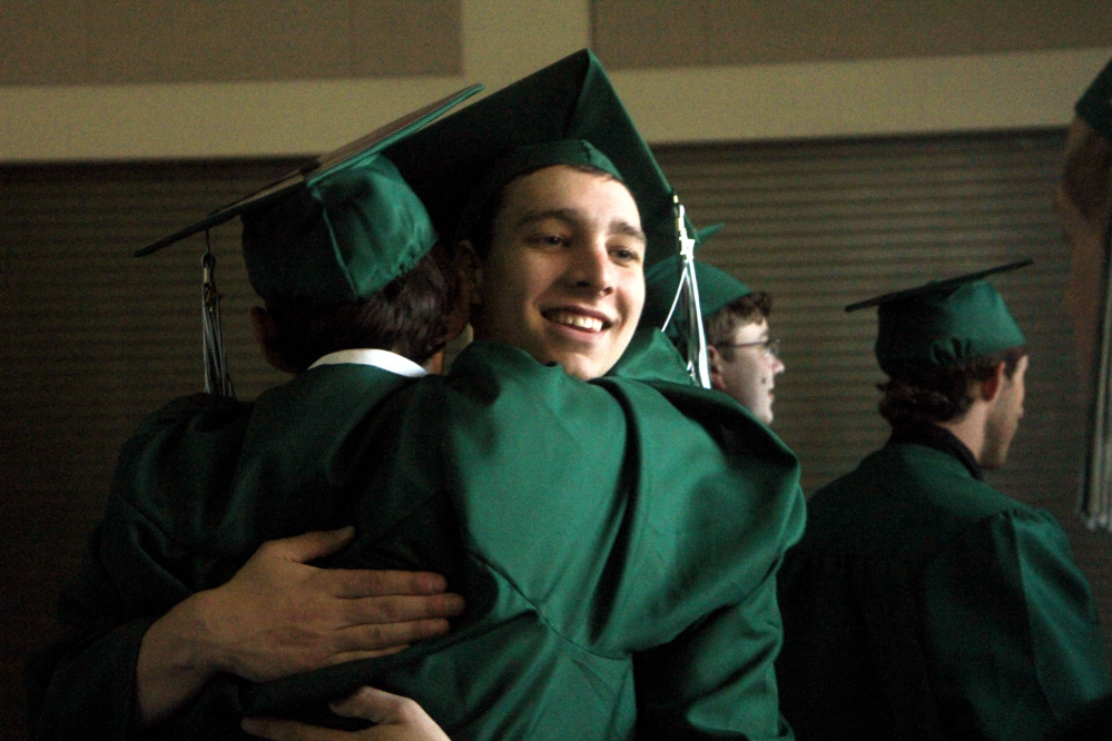 Winthrop High School senior Nickk Child hugs a classmate prior to commencement exercises on Sunday.