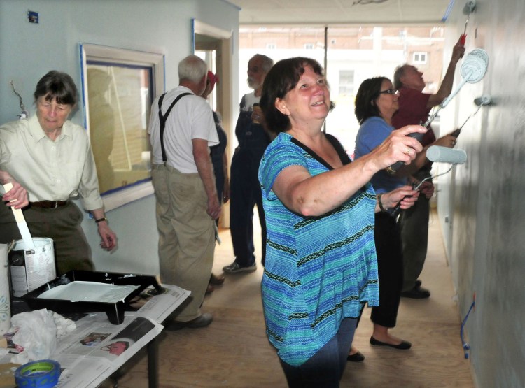 REM volunteers, including Diane Louten, right, armed with two paint rollers, put a fresh coat of paint on the new REM offices Tuesday on Temple Street in Waterville. At left is Co-executive Director Jackie Dalton.