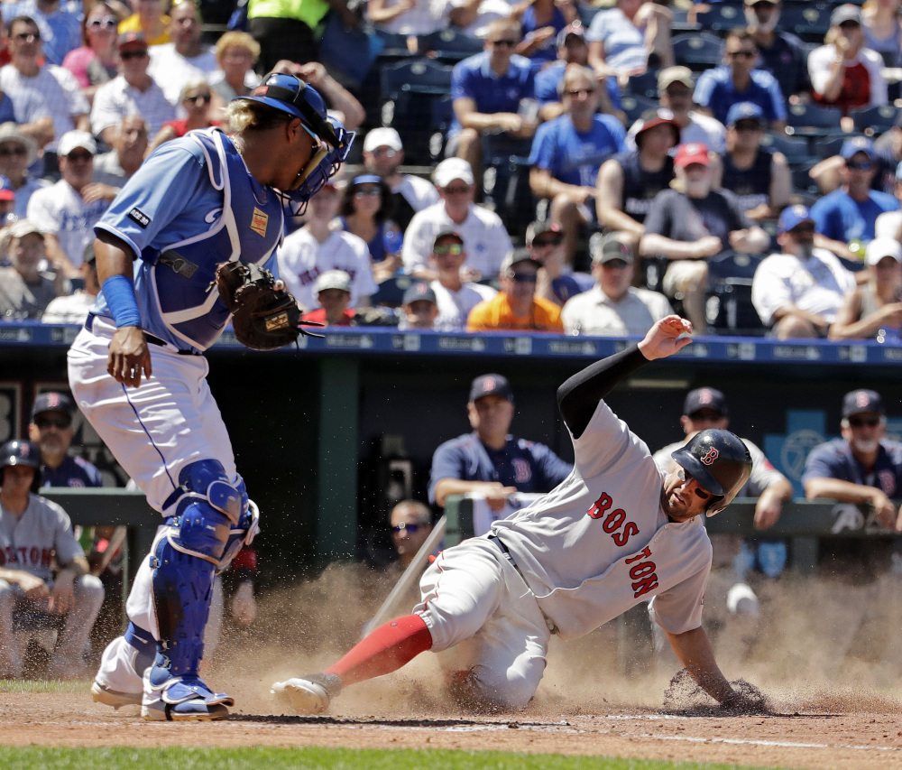 Boston Red Sox infielder Deven Marrero beats the tag by Kansas City catcher Salvador Perez to score on a catching error by first baseman Cheslor Cuthbert during the fifth inning Wednesday.