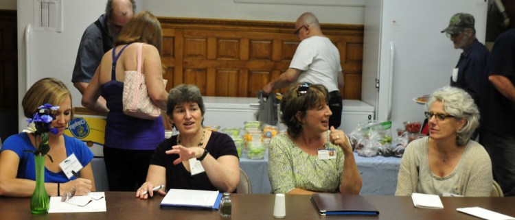 Officials with the EPA and other agencies held a meeting during lunch at the Sacred Heart Soup Kitchen in Waterville on Monday. The group is touring Waterville facilities that contribute to a healthy environment. As clients select donated food in back, Stephanie Bertaina, left, of the EPA, Fran Mullin of Healthy Northern Kennebec, Ellen Wells of Inland Hospital and Chris Beling of the EPA discuss issues.