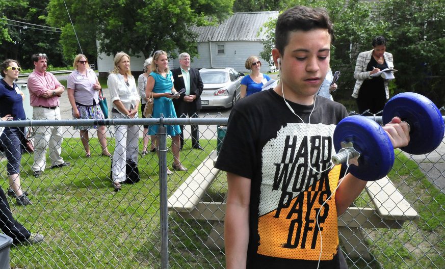 As members of agencies taking part in the EPA Healthy Places for Healthy People program listen to directors of the South End Teen Center on Monday in Waterville, Jordan Carpenter works with weights at the facility.