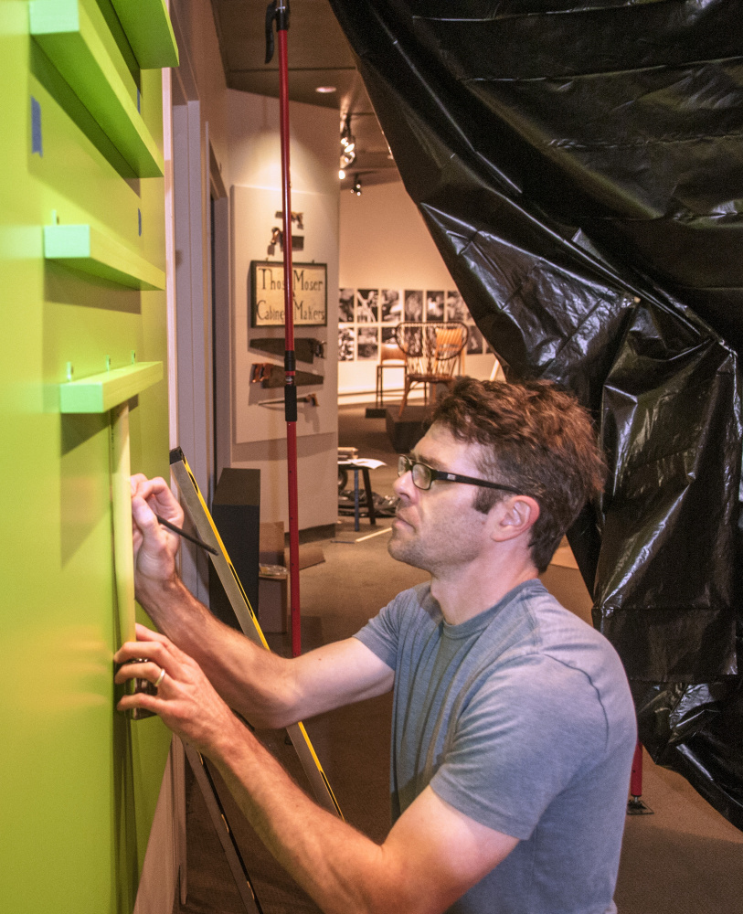 Staff photo by Joe Phelan
Ryan Walker, an exhibits preparator at the Maine State Museum, builds shelves for levels and other tools in the entryway to the "Thos. Moser: Legacy in Wood" exhibition under construction on Tuesday at the museum in Augusta.