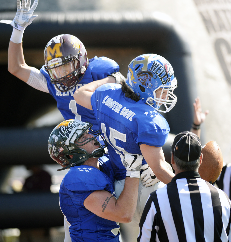Steven Gilbert (15) of Oak Hill is swarmed by teammates after scoring a touchdown during the Lobster Bowl on Saturday at Thornton Academy in Saco.