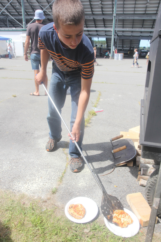 Josiah Lackey, 13, of Parkman, slides a couple of wood-fire pizzas onto plates Saturday at the annual Artisan Bread Fair at the Skowhegan fairgrounds.