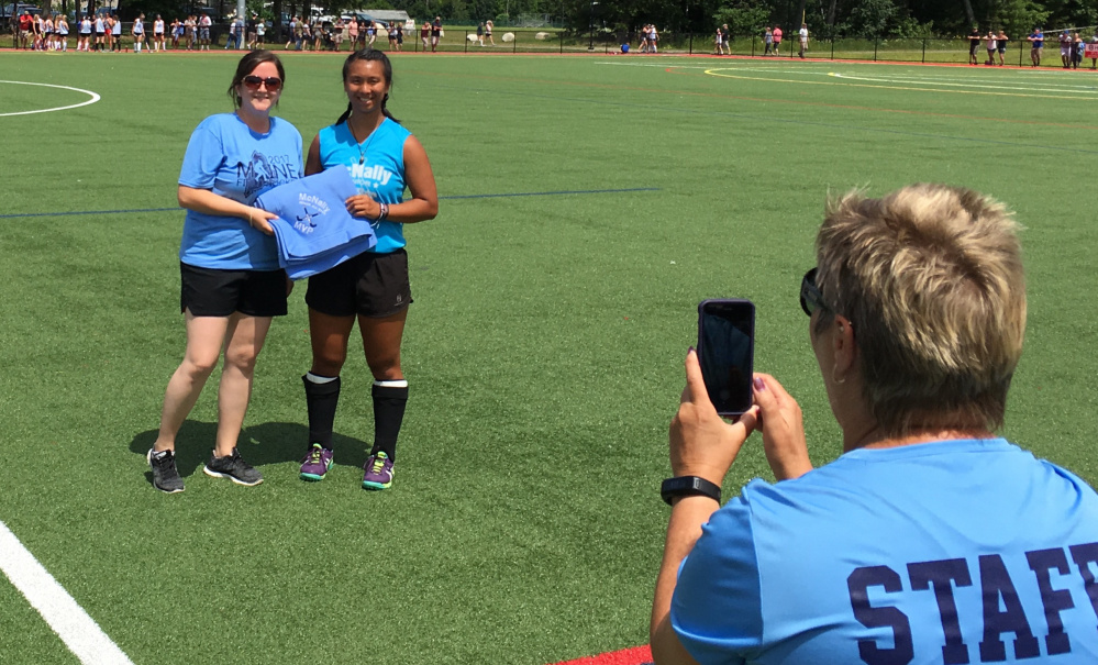 Messalonskee's Ally Corbett accepts her trophy as the Faith Littlefield MVP player for the North squad during the McNally Senior All-Star Field Hockey game Saturday in Waterville.