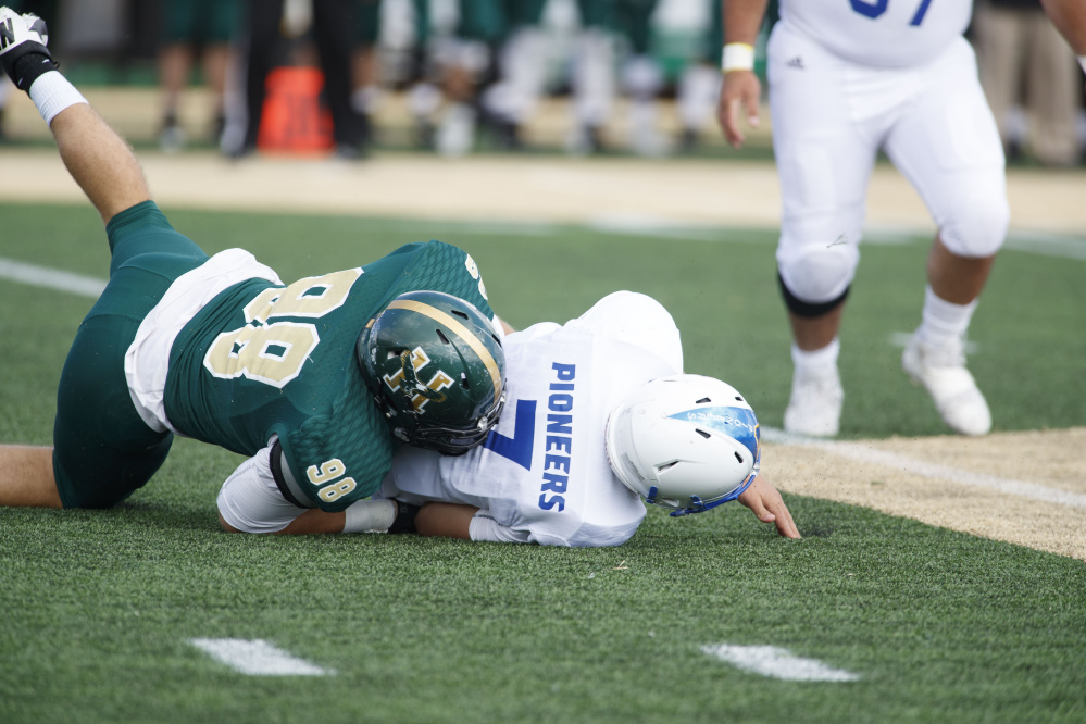 Oak Hill graduate and Husson defensive lineman Luke Washburn brings down Alfred State quarterback Hunter Evingham during a game last season in Bangor.