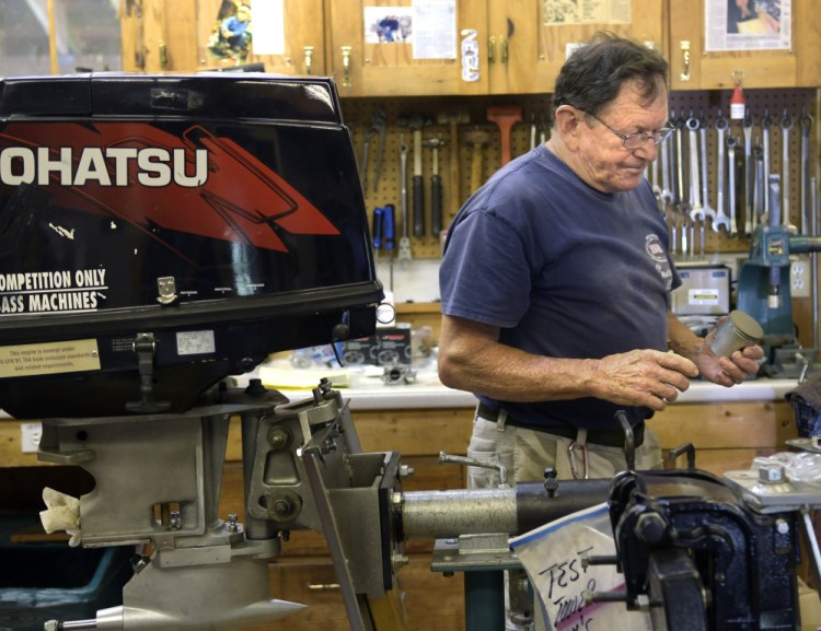 Alex Poliakoff carries a coated piston shaft for an engine he's building for a race boat on Wednesday at his shop in Bowdoinham.