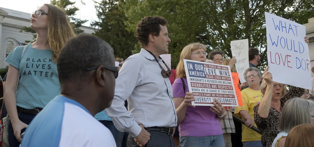 People hold signs and sing songs at the State House on Monday in Augusta. During the rally held in support for Charlottesville, Virginia, the crowd also started several chants, including, "No hate. No fear. Everyone is welcome here," and "Silence is violence, no justice, no peace."