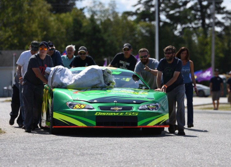 Jeff Taylor's crew pushes his car through the Oxford Plains Speedway pit area on Saturday morning.