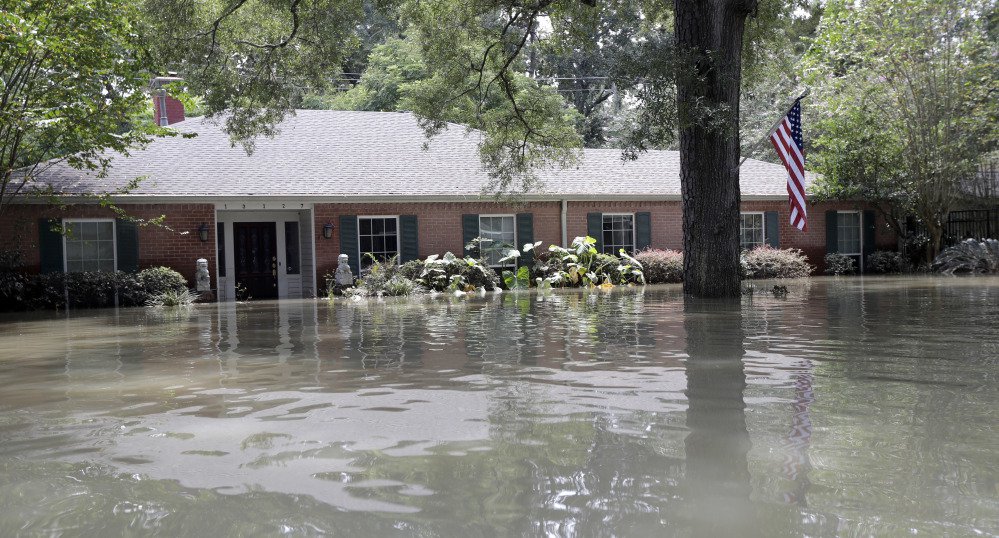 A flag hangs outside a flooded home Monday near the Addicks and Barker Reservoirs in Houston. The historic storm inundated exclusive neighborhoods as well as low-lying apartments for the poor.