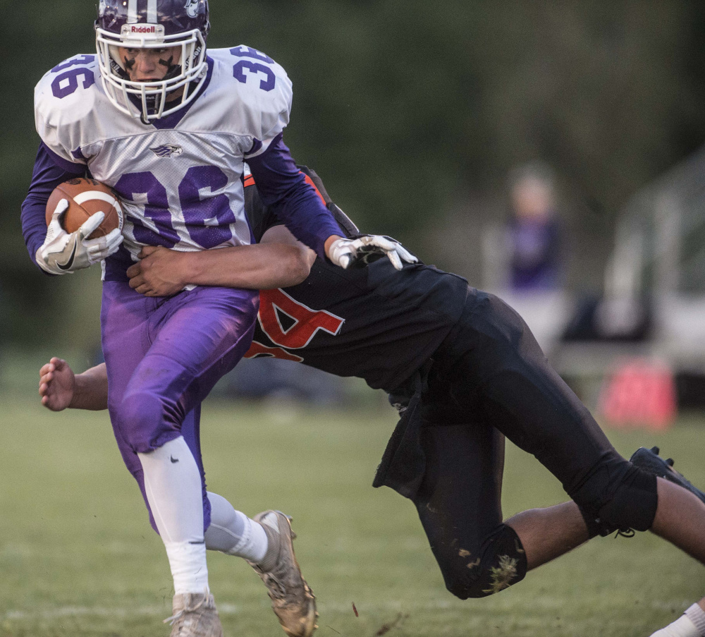 Marshwood senior Kyle Gladden (36) is tackled by Skowhegan defender Kobe Houghton during a Class B game Friday night at Clark Field in Skowhegan.