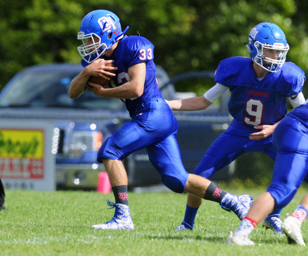 Oak Hill running back Cruz Poirier (33) takes a handoff from quarterback Gavin Rawstron during Saturday's game against Yarmouth in Wales.