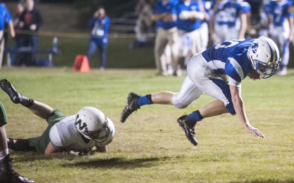 Madison's Evan Bess, right, gets tripped up by Winthrop/Monmouth defender Carson Camick during a Class D South game Friday night at Rudman Field in Madison.