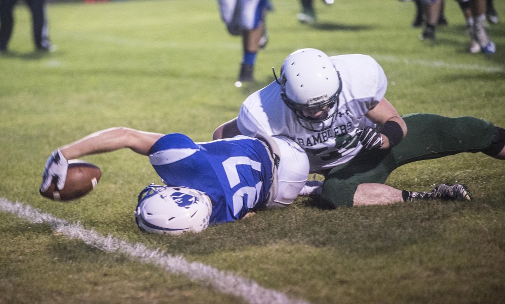 Madison receiver Sean Whalen scores a touchdown as Winthrop/Monmouth defender Morgan Bellemare goes for the tackle during a Class D South game Friday night at Rudman Field in Madison.