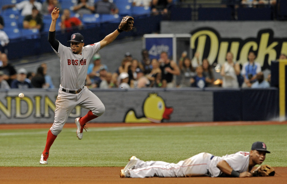 Boston shortstop Xander Bogaerts, left, and Rafael Devers cannot stop a ground ball single hit by Tampa Bay's Evan Longoria that drove in Jesus Sucre from third base during the fifth inning Sunda in St. Petersburg, Florida.