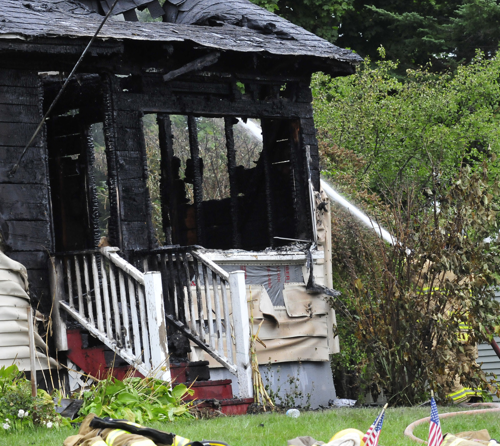 A firefighter sprays water on the burning home at 231 Lakeview Drive in China that was destroyed by fire on Monday.