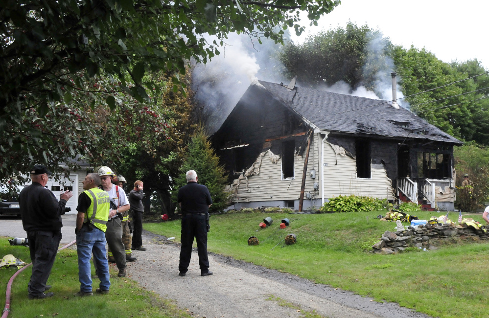 Ken McMaster, left, of the Office of State Fire Marshal, speaks with firefighters outside the home at 231 Lakeview Drive in China that was destroyed by fire on Monday.