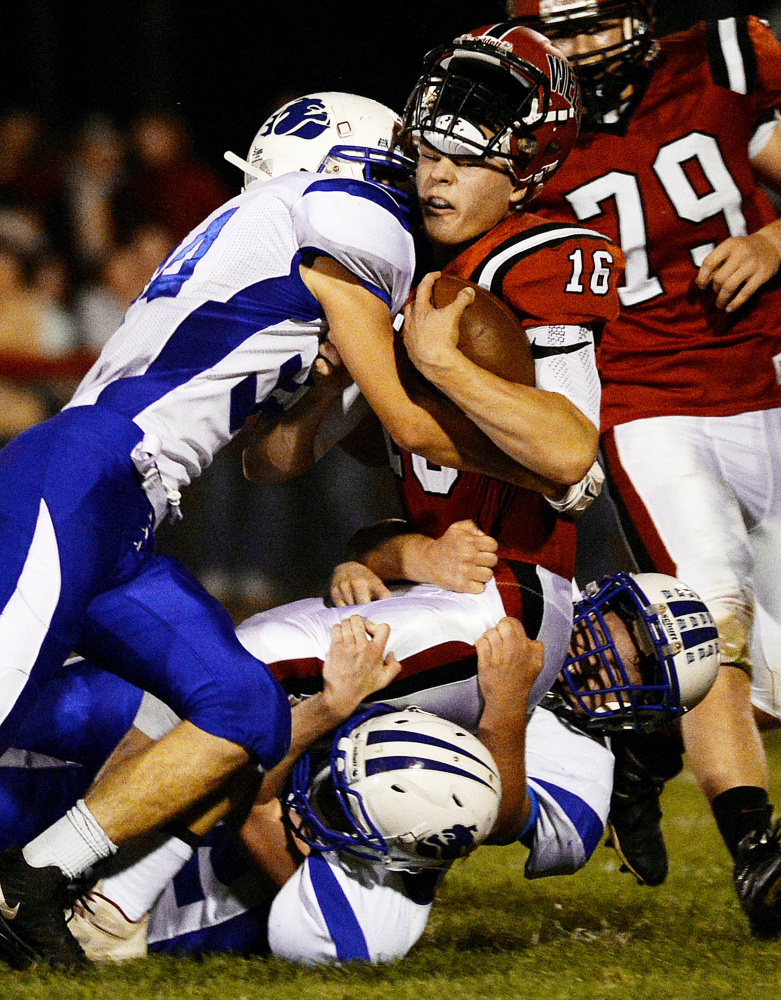 Wells running back Michael Wrigley gets his helmet knocked off by Madison defender Jacob Meader, left, during a Class D South game Friday night.