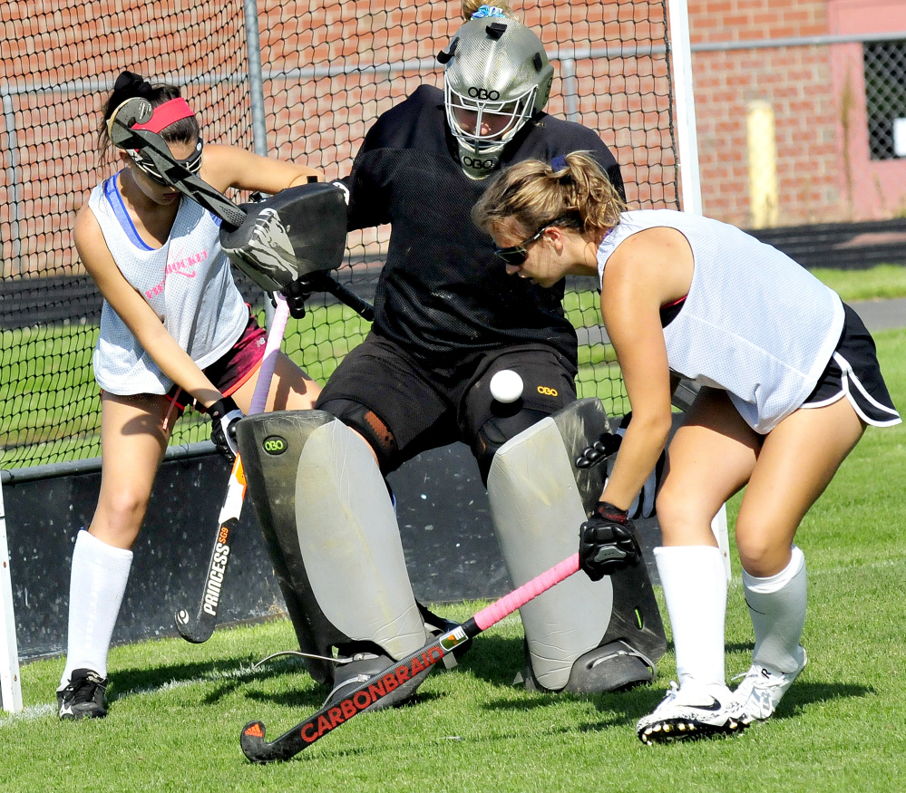 Skowhegan field hockey goalie Leah Savage makes a save as sweeper Haley Carter, left, and Elizabeth York apply pressure during an August practice in Skowhegan.