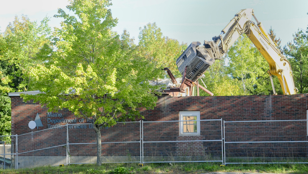 An excavator with a claw rips apart an old Department of Transportation building Friday in Augusta, where developers plan to build two new office buildings and lease space back to the state on Capitol Street.