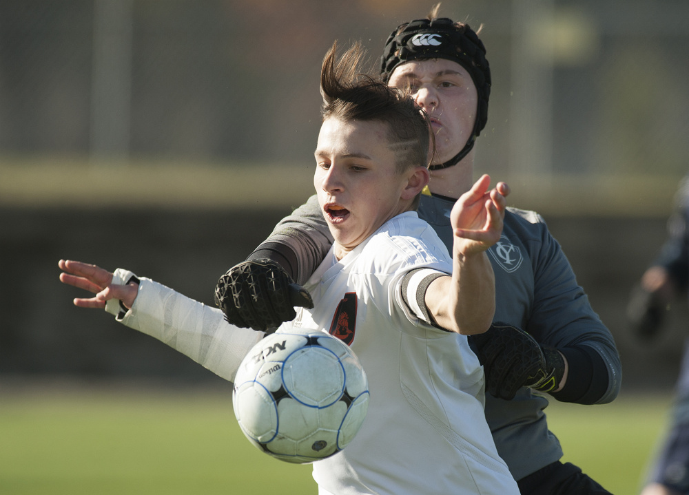 Yarmouth goalie Cal Owen punches the ball away from Winslow's Jake Warn during second half action during the Class B boys State Championship in Hampden last year.