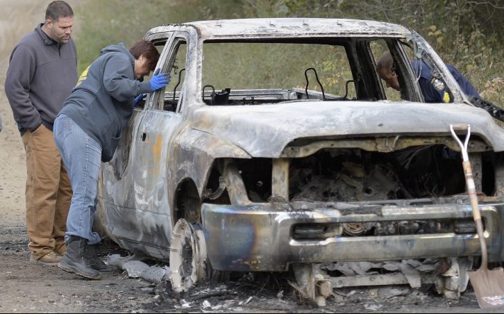 Investigators examine a charred pickup truck containing a body Saturday on Lincoln Street in Richmond.