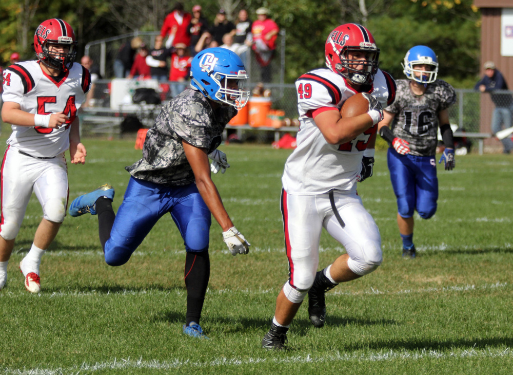 Wells High School's Nolan Potter runs past Oak Hill High School's Darryn Bailey for a 19-yard touchdown in the first half in Wales on Saturday.
