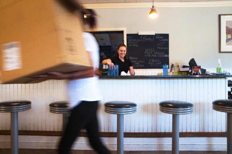 Chantel Ruby, a server at Bernie's Foreside, center, cleans a countertop at the Falmouth diner as Christy Stegner hauls in a box of table decorations for the evening, when the space is transformed into Esidore's Bistro, where Stegner is front-of-house manager.