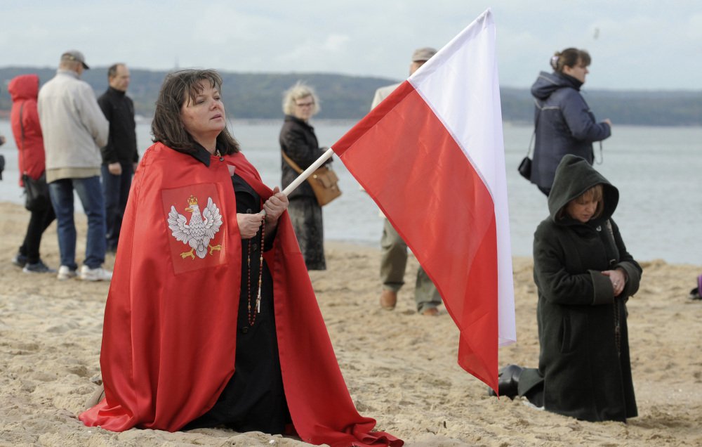 A worshipper holds a Polish national flag during a rosary prayer in Gdansk, Poland, Saturday. Hundreds of thousands of Polish Catholic faithful prayed the rosary around Poland's borders.