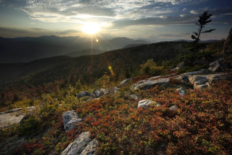 The sun begins to set in this view from South Moat Mountain in Albany, N.H. Longtime leaf watchers say the leaves this fall are dull and weeks behind schedule in reaching their peak.