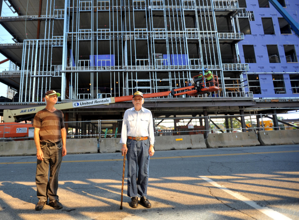 Raymond LaPointe, left, and Clifford Hebert, right, standing in front of the new Colby College building in downtown Waterville on Wednesday, have watched the building go up from the start and have gotten to know the construction workers in the process..