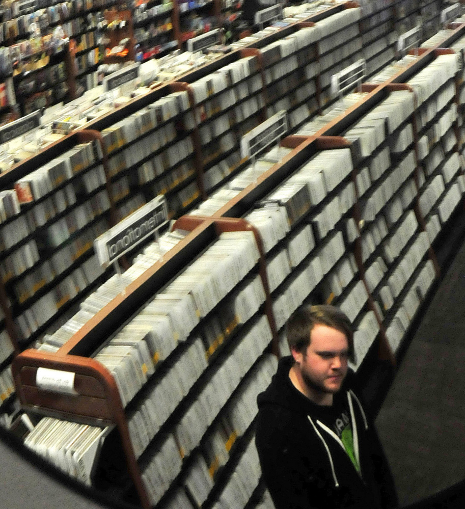 Standing next to a wall of CDs, Nick Murray speaks about the unexpected death of musician Tom Petty on Tuesday at the Bull Moose Music store in Waterville.