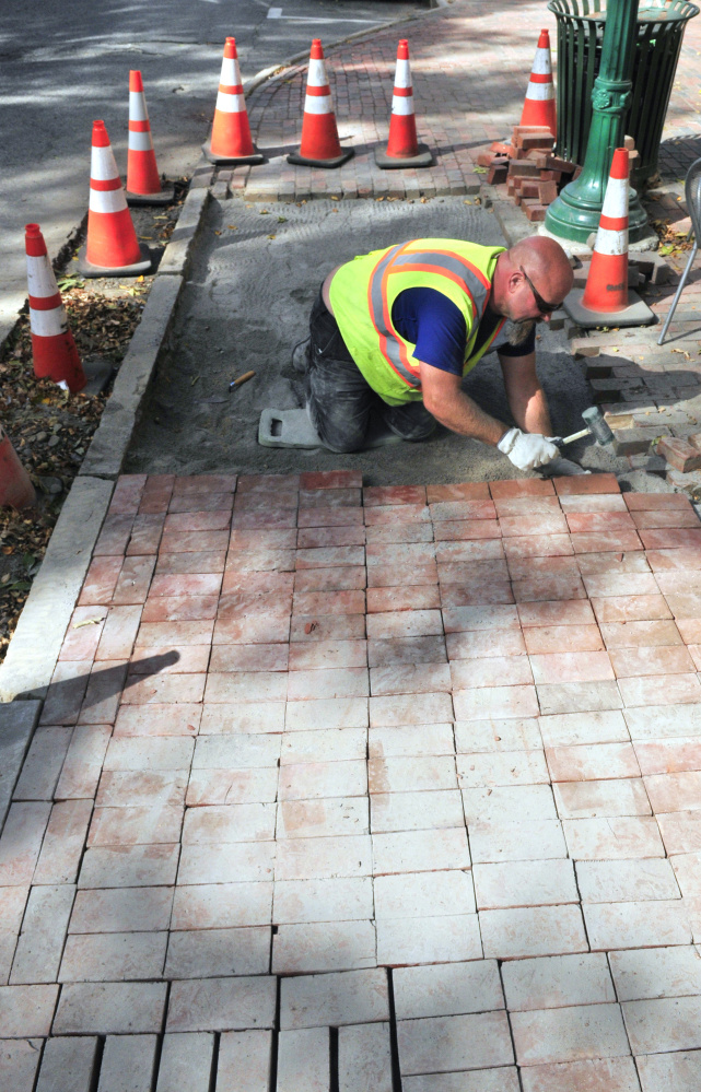 City worker Dan Robideau rebuilds the brick sidewalk in front Gardiner Co-op on Tuesday on Water Street in Gardiner.