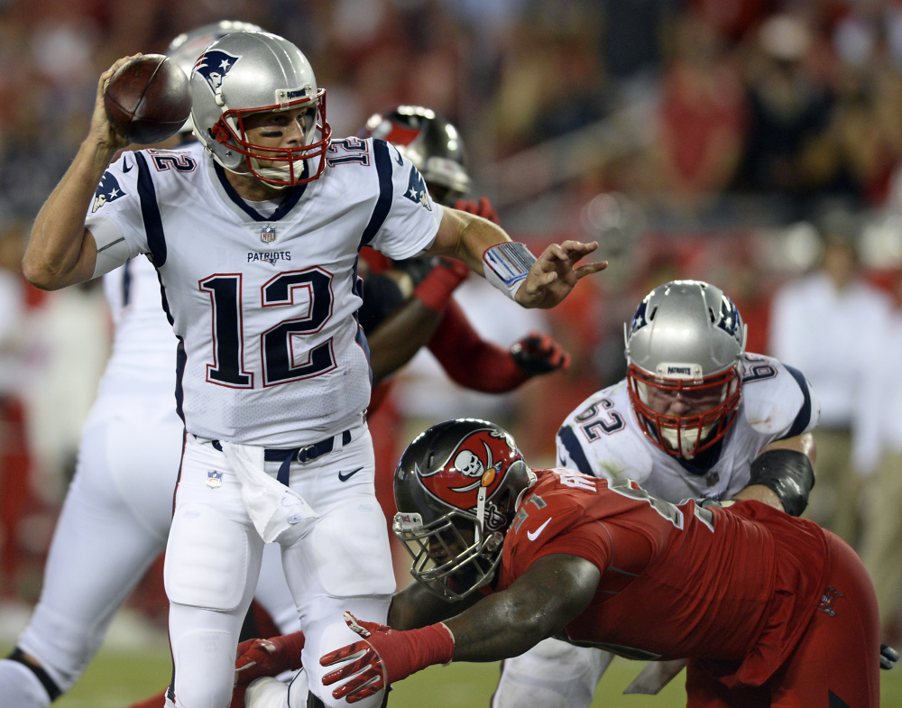 New England Patriots quarterback Tom Brady (12) looks to throw a pass as he is pressured by Tampa Bay defensive end Robert Ayers during the first half Thursday in Tampa.