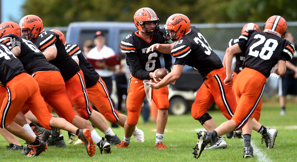 Winslow High School quarterback Ryan Gagnon (6) hands the ball off to Ryan Fredette (33) against Gardiner on Saturday in Winslow.