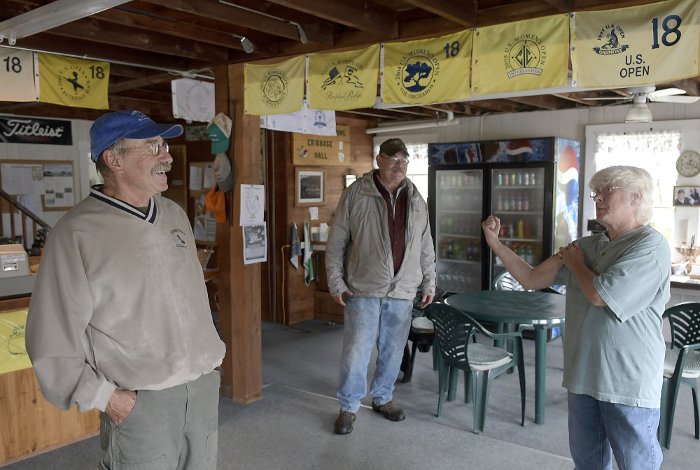 Shirley Everhart flexes her muscles while offering to assist Bill, left, and Dave Sylvester repair the greens at Cobbossee Colony Golf Course in Monmouth on Monday. The Sylvester family discovered Monday that several parts of their course were damaged by golf carts overnight. Everhart, of Monmouth, said she is strong and willing to do anything to help her neighbors.