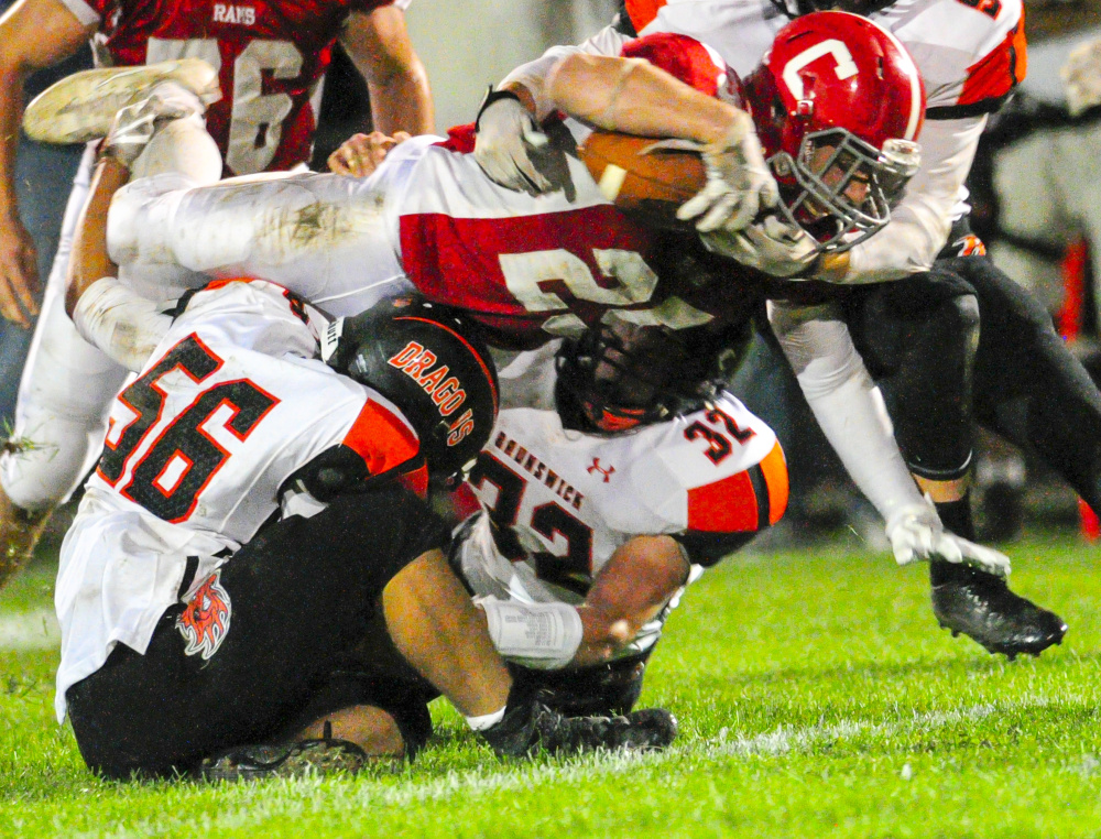 Cony running back Logan Leadbetter stretches out for some extra yards as a pair of Brunswick defenders converge on the tackle during a Pine Tree Conference Class B game earlier this season at Alumni Field in Augusta.