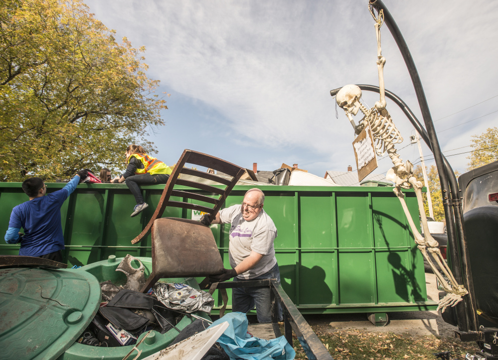Ralph Merrow unloads his trailer of collected garbage into a dumpster Saturday with the help of Colby College staff members and students during an areawide cleanup coordinated by the college and the South End Neighborhood Association's Quality of Life Committee on Water Street in Waterville's South End neighborhood.
