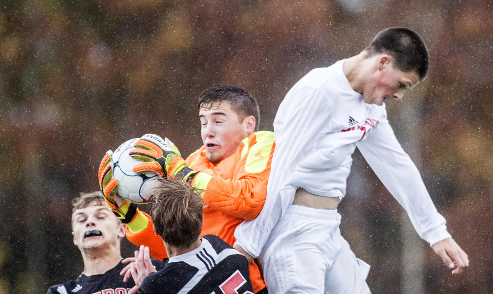 Lisbon goalie Jonah Sautter, center, makes a save on a corner kick as Hall-Dale's Matt Albert, right, tries to head the ball into the goal in a Class C South quarterfinal game Thursday at Thomas College in Waterville.