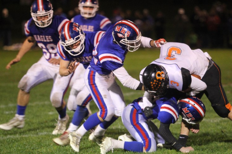 Brewer High School's Brandon Glidden is brought down by Messalonskee defender Josh Goff (bottom) and a host of Eagle defenders during first-half action in Oakland on Friday night.