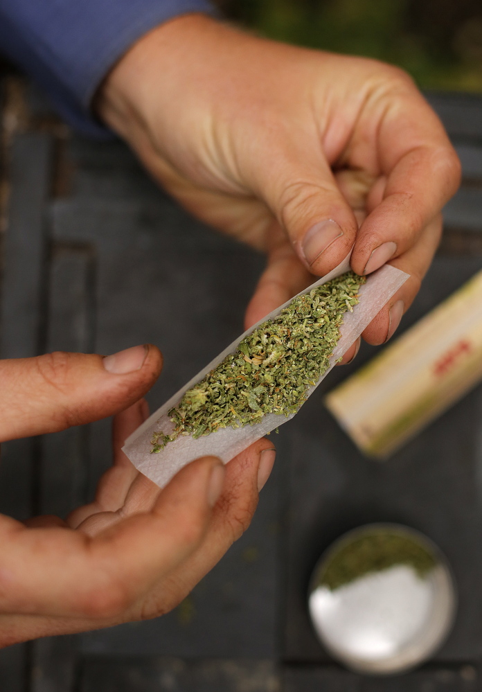 A smoker rolls a marijuana cigarette in Portland on Oct. 11, 2013. Voters in Madison will be asked to decide Nov. 7 whether to ban all types of retail marijuana establishments in that town.