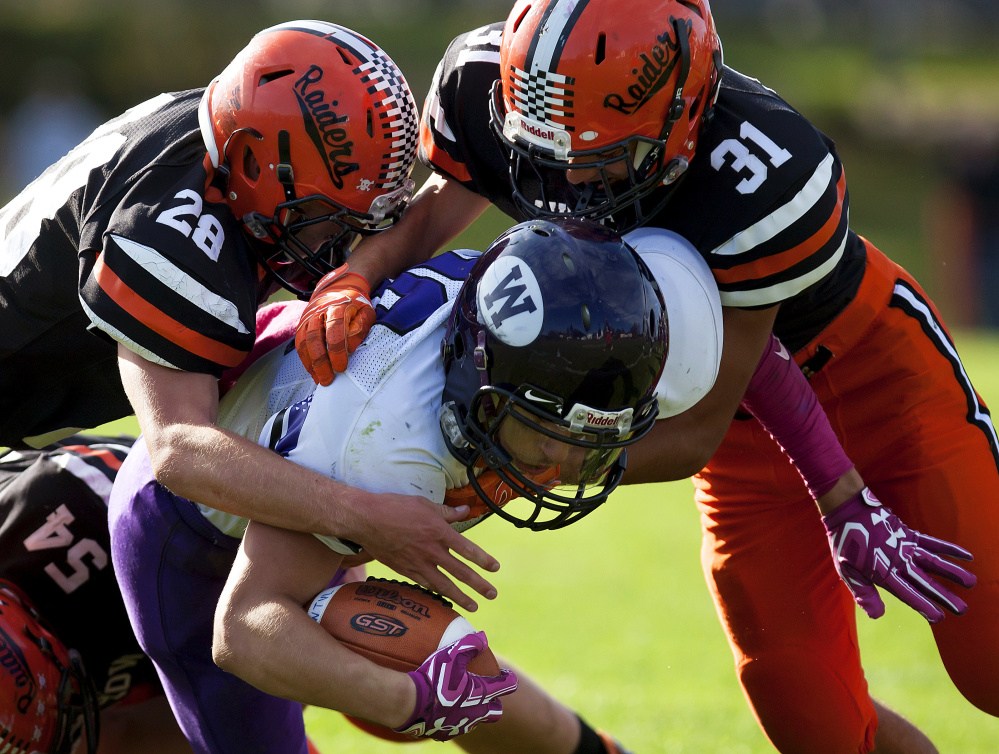 Winslow defenders Isaiah Goldsmith, left,  and Tyler Crayton bring down Waterville's Nicholas Wildhaber during a Class C North quarterfinal game Saturday at Poulin Field in Winslow.